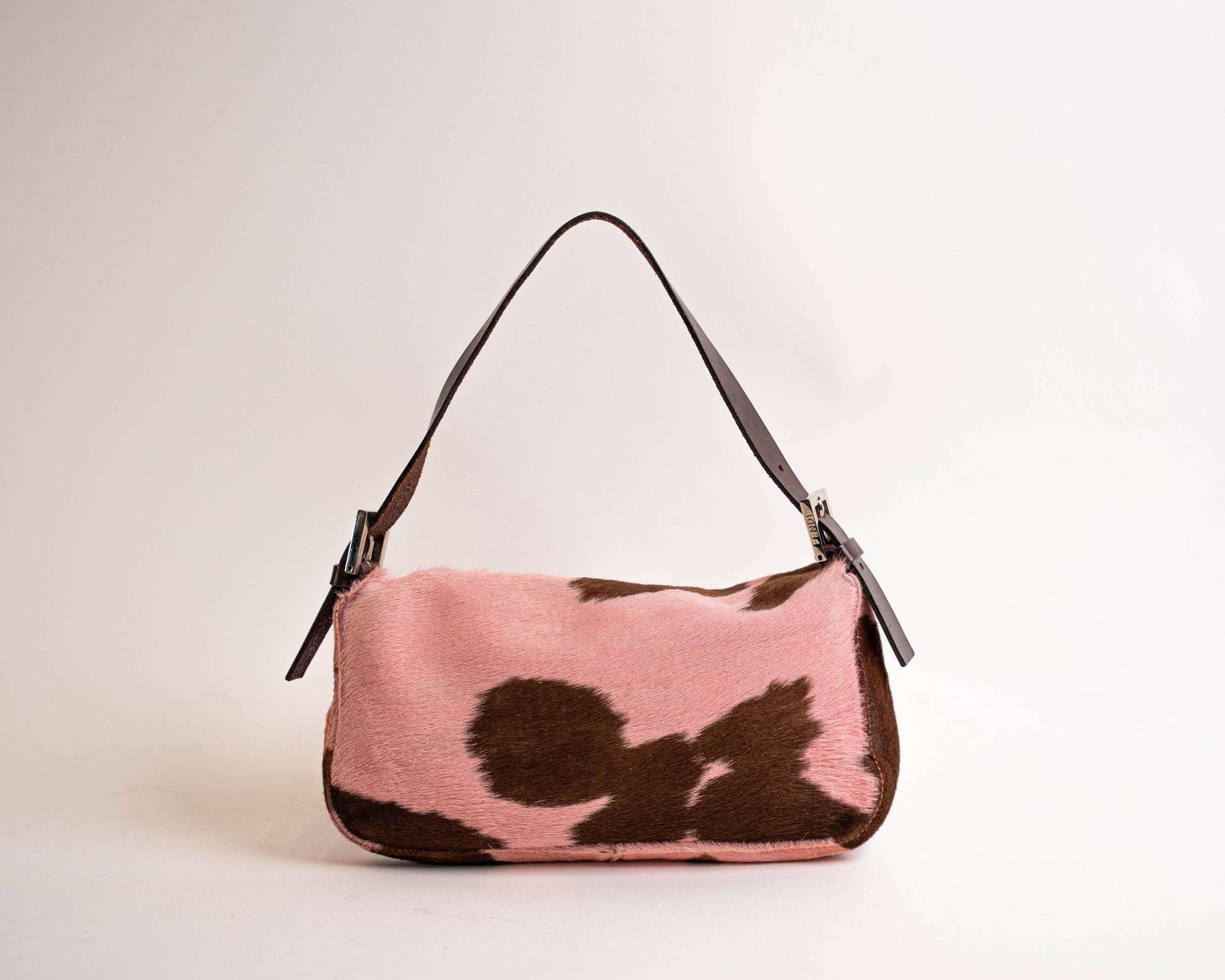 Pink and brown cow print handbag on a light beige background